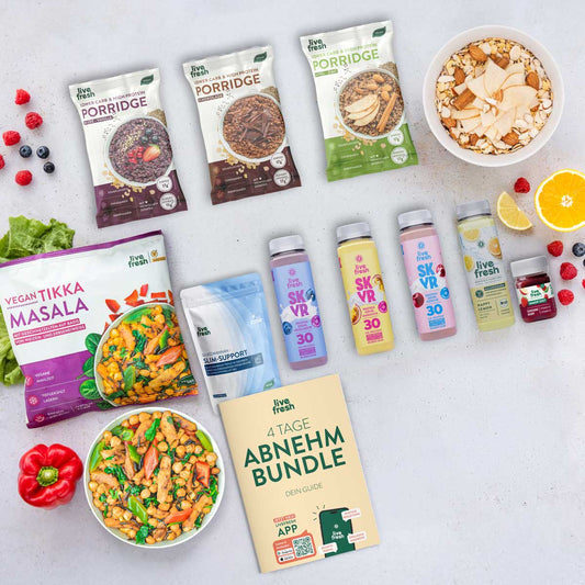 LiveFresh Abnehmbundle mit Porridge in verschiedenen Sorten. Vegan Tikka Masala. Slim Support. Protein Drinks. Funktionsgetränk. Immun Shot und dem Guide mit der Aufschrift "4 Tage Abnehm Bundle. Dein Guide". Dazu sind fertige Mahlzeiten. Obst und eine Schale Porridge angerichtet.