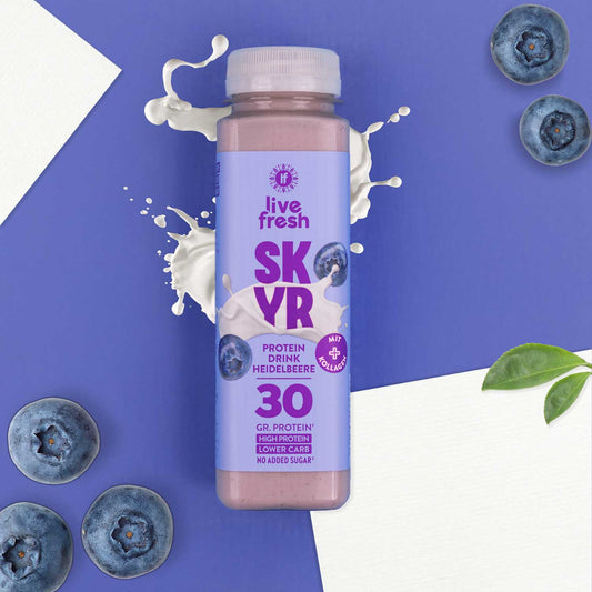 Flasche Live Fresh Skyr Protein Drink Heidelbeere auf lila Hintergrund mit Blaubeeren und Milchspritzer.