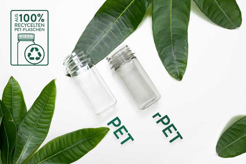 Das Bild zeigt zwei Flaschen nebeneinander, eine aus PET und eine aus recyceltem PET (rPET), umgeben von großen, grünen Blättern. Ein Logo auf der linken Seite hebt hervor, dass die Flaschen aus 100 % recyceltem Material bestehen.