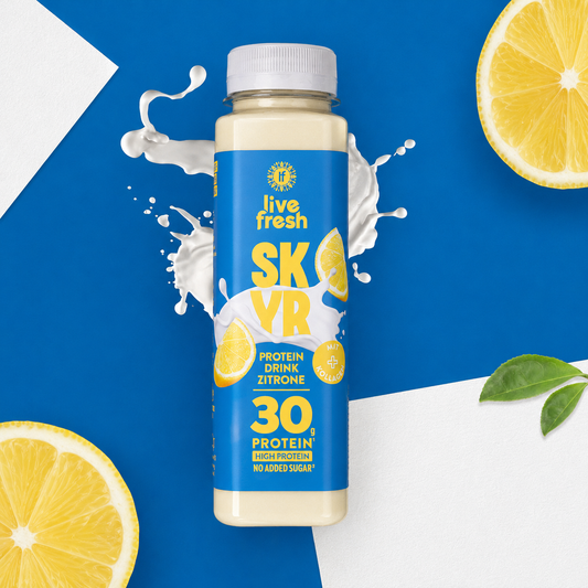 „live fresh SKYR“ Protein Drink Zitrone vor blau weißem Hintergrund mit Milchspritzern und Zitronenscheiben. Auf der Flasche steht „30 g Protein“, „High Protein“, „No Added Sugar“ sowie „mit Kollagen“.