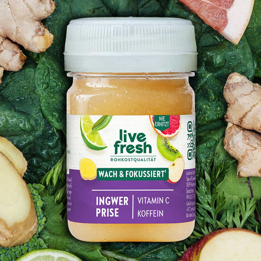 Heller LiveFresh Shot umgeben von Blattgemüse Ingwer Apfel Limette und Grapefruit. Auf dem Etikett steht "live fresh Rohkostqualität Wach und Fokussiert Ingwer Prise Vitamin C Koffein".